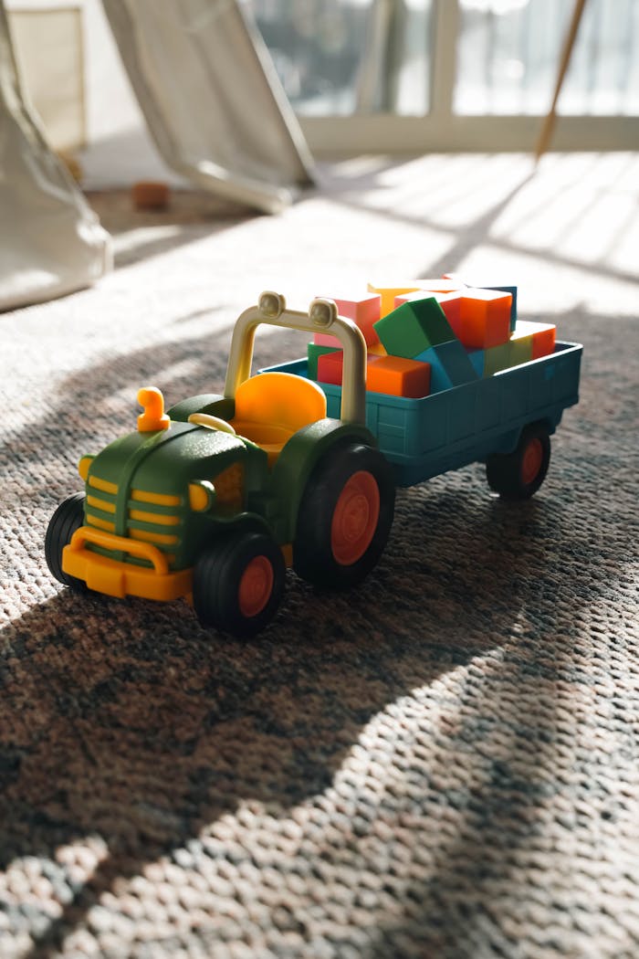 A vibrant toy tractor with blocks on a carpeted floor, bathed in warm sunlight.