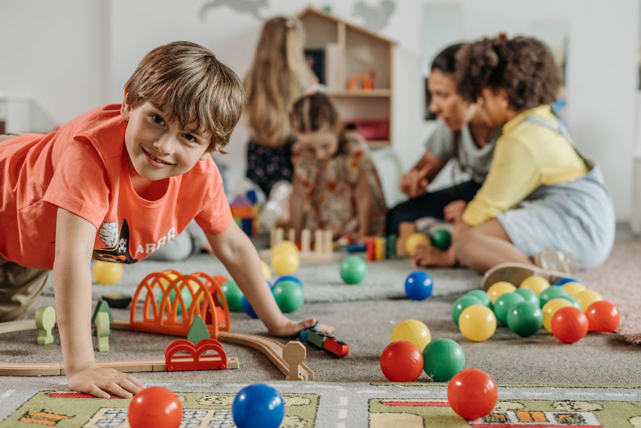 Projekte und Ziele Happy children and a caregiver playing with colorful toys in a lively indoor playroom setting.